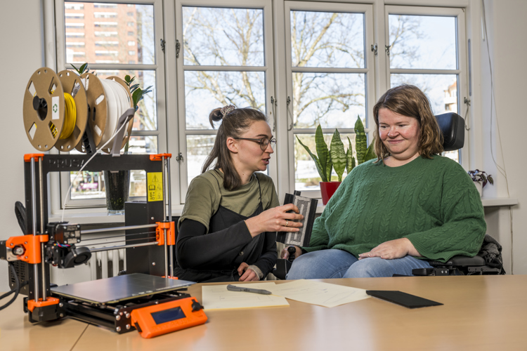 Kvinde i kørestol får hjælp til at desine et 3-D printet hjælpemiddel